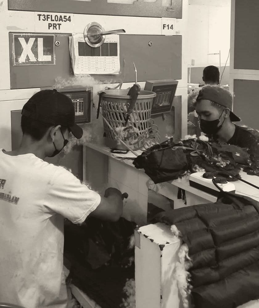 A tailor steam-pressing a finished garment at the finishing station